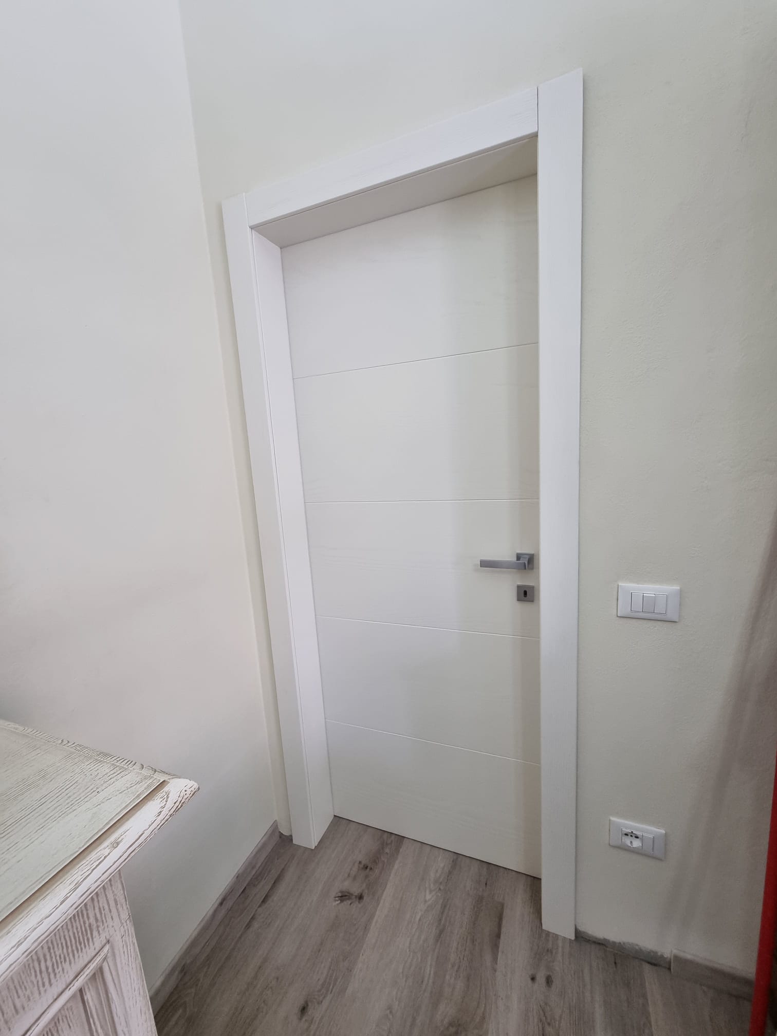 Porta interna bianca a fianco di un lavabo
