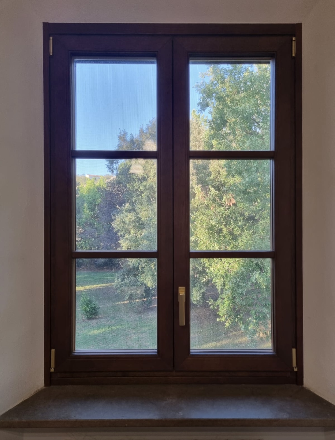 La finestra color legno vista dall’interno, con luce sul davanzale